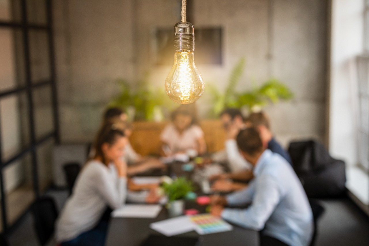 Young creative business people meeting at office. Young business people are discussing together a new startup project. A glowing light bulb as a new idea.
